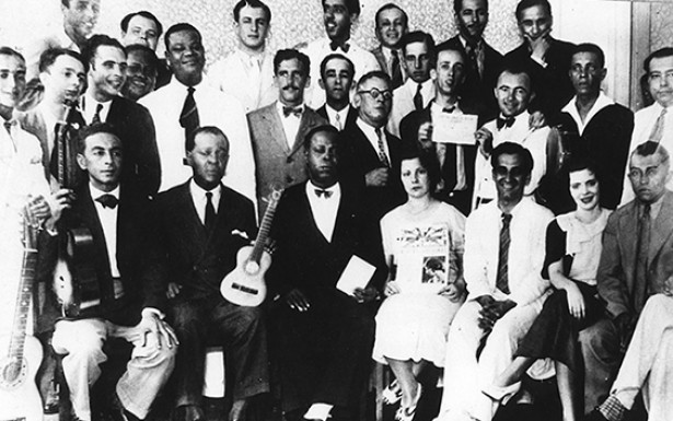  <strong> Ademar Casé </strong> (o último sentado a partir da esquerda) e músicos que participavam do “Programa Casé”, em 1932. Entre eles, Noel Rosa (o segundo em pé) e Pixinguinha (o quarto)