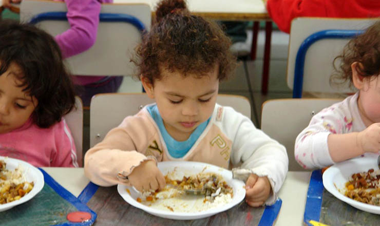  <strong> Crianças se alimentam em cozinha popular: </strong> políticas de educação e saúde elevam o país ao patamar de desenvolvimento humano elevado