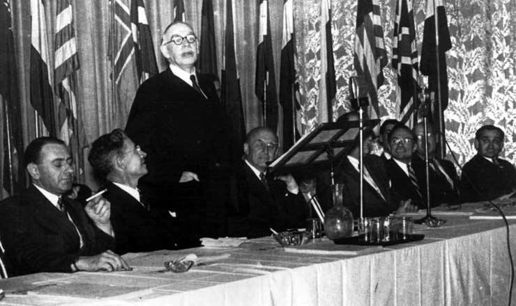  <strong> John Maynard Keynes, autor da proposta britânica, discursa </strong> em Bretton Woods ao lado de Harry Dexter White (à sua esquerda), autor da proposta norte-americana