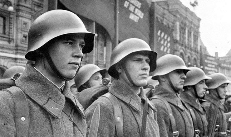  <strong> Soldados do Exército Vermelho mobilizados para a defesa do território soviético, </strong> em 1941; atrás deles, uma faixa exibe, em inglês, o slogan comunista "Trabalhadores do mundo, uni-vos!"