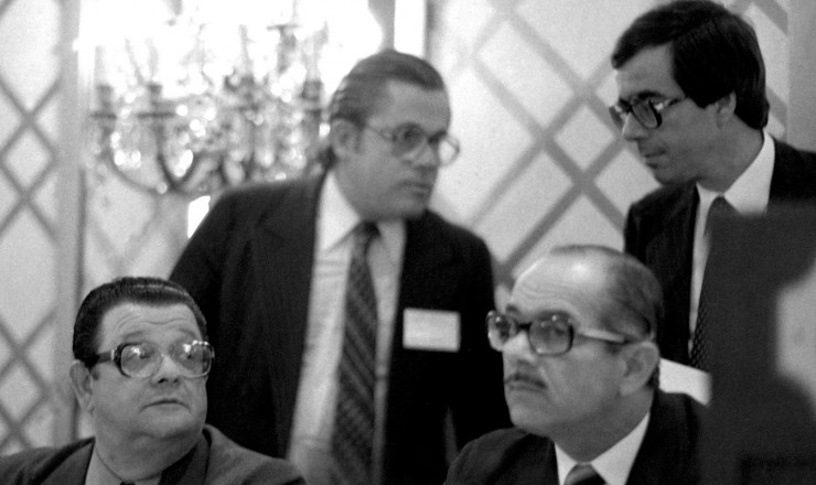  <strong>  Delfim Netto </strong> (à esq.), Ernane Galvêas (à dir.) e Carlos Langoni (atrás, à dir.) durante reunião de negociação com o FMI e bancos credores, em Nova York, em fevereiro de 1983